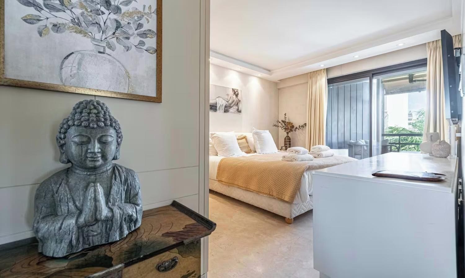 A bedroom with a bed, a statue, and a painting.