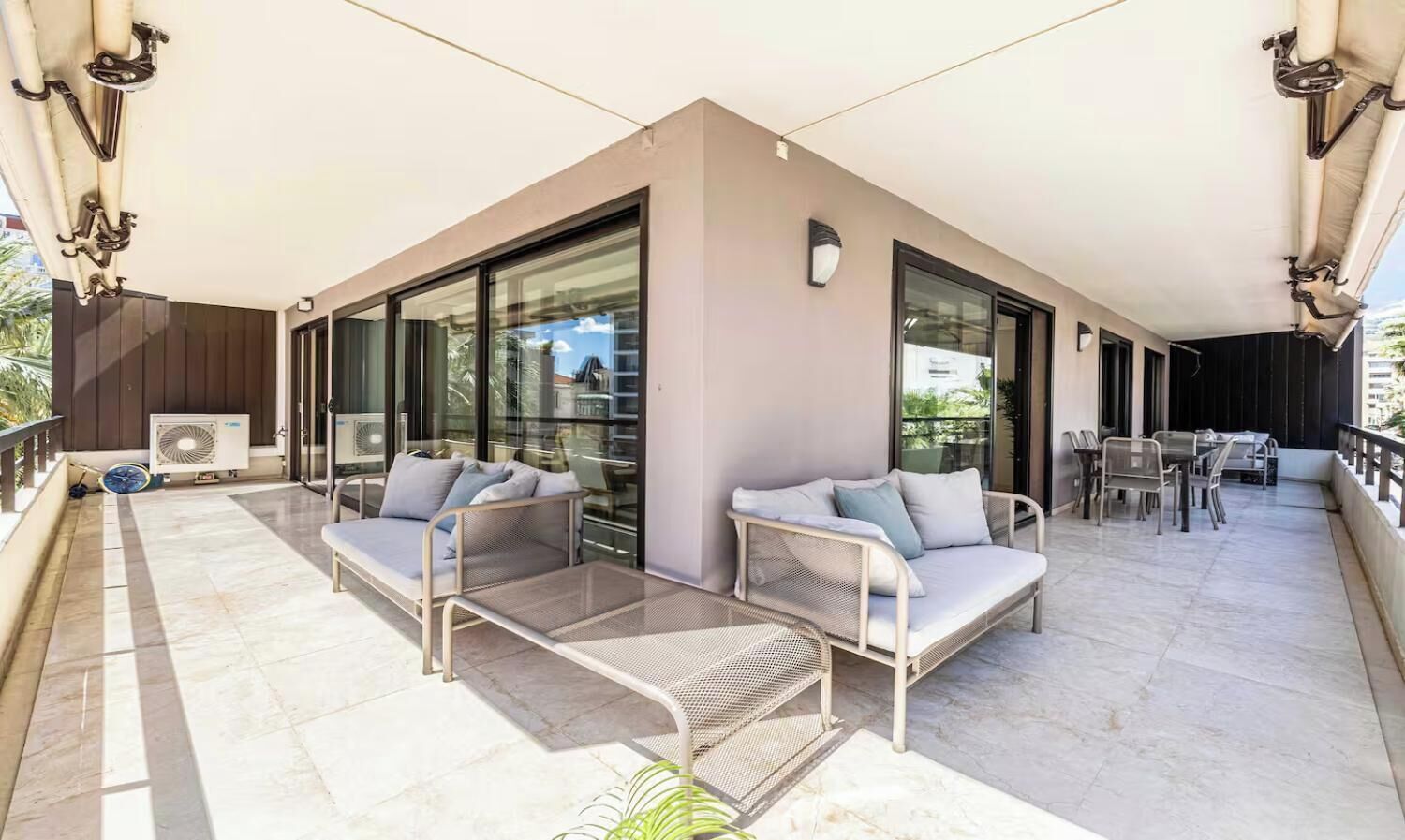 A balcony with two sofas, a table, and chairs.