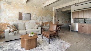 Un salon avec un canapé, un fauteuil, une table basse et un tableau accroché au mur.