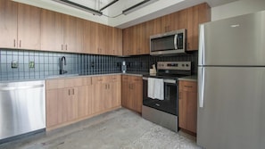 Une cuisine moderne avec des meubles en bois, un réfrigérateur en acier inoxydable, un four à micro-ondes et un four traditionnel.