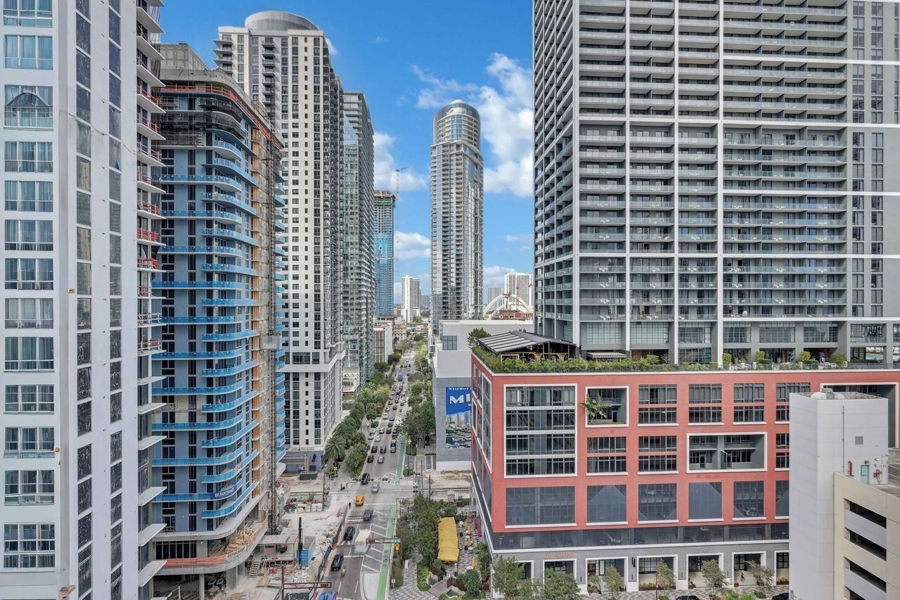 Uma área urbana com edifícios altos, incluindo um imponente arranha-céu cilíndrico e vários prédios residenciais.