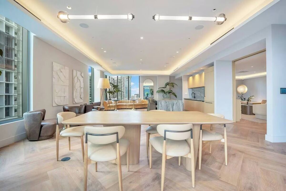 A modern interior with a large dining table, comfortable seating, and a view of the city.