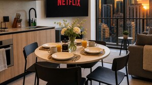 A modern kitchen with a dining area, a large window with a city view, and a flat-screen TV displaying 'NETFLIX'. - Miami Luxe Suites (Miami)