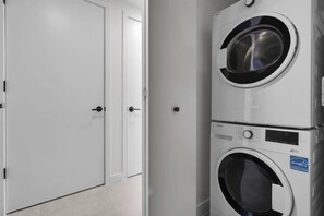A laundry room with stacked washing machines and a closed door. - Miami Luxe Suites (Miami)
