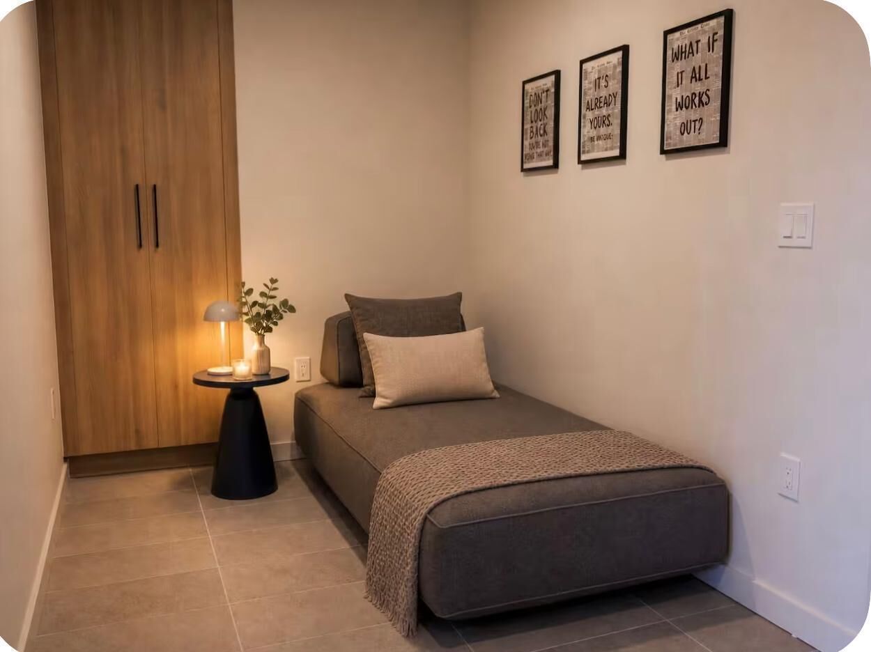 Een slaapkamer met een bed, nachtkastje, lamp en kledingkast.