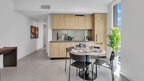 A modern kitchen with a dining area, featuring a round table with chairs, a built-in oven, and a large window with a view. - Miami Luxe Suites (Miami)