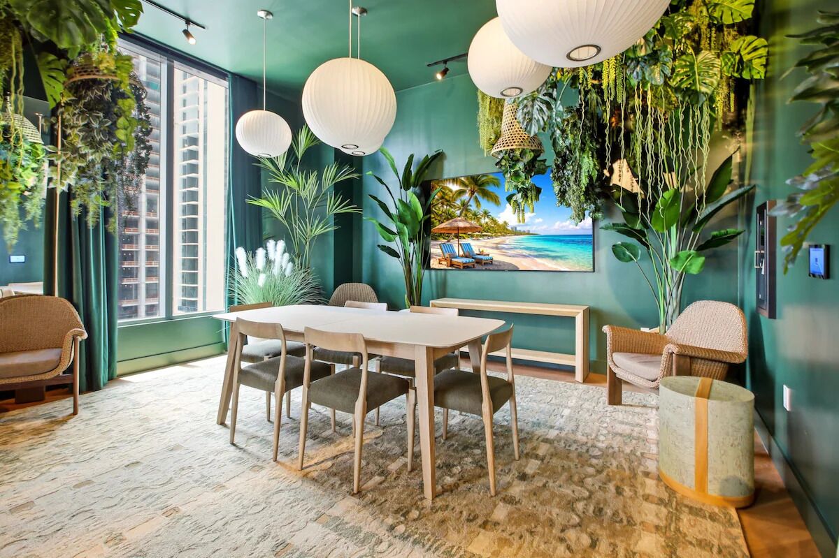 A room with a dining table, chairs, a sofa, a TV, and a large window.