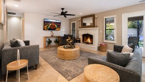 A modern living room with a fireplace, comfortable seating, and a television. - Luxury 5BR Retreat, Heated Pool, Spa, Sport Court, Putting Green & Game Rooms (Scottsdale)