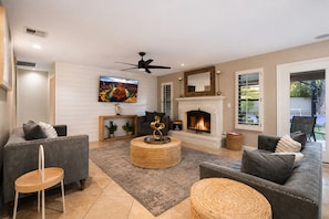A modern living room with a fireplace, comfortable seating, and a television. - Luxury 5BR Retreat, Heated Pool, Spa, Sport Court, Putting Green & Game Rooms (Scottsdale)