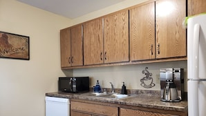 A kitchen with wooden cabinets, a dishwasher, a coffee maker, and a microwave.