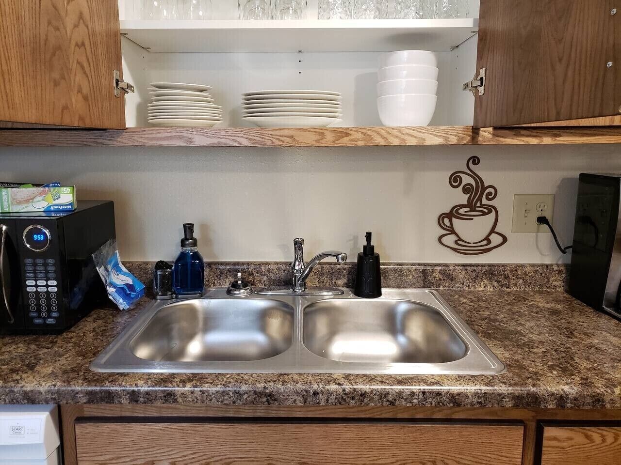A kitchen with a double stainless steel sink, a microwave, and a coffee machine.