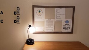 A bulletin board with various notices, a desk lamp, and a wooden table.