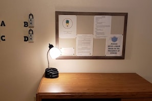 A bulletin board with various notices, a desk lamp, and a wooden table.