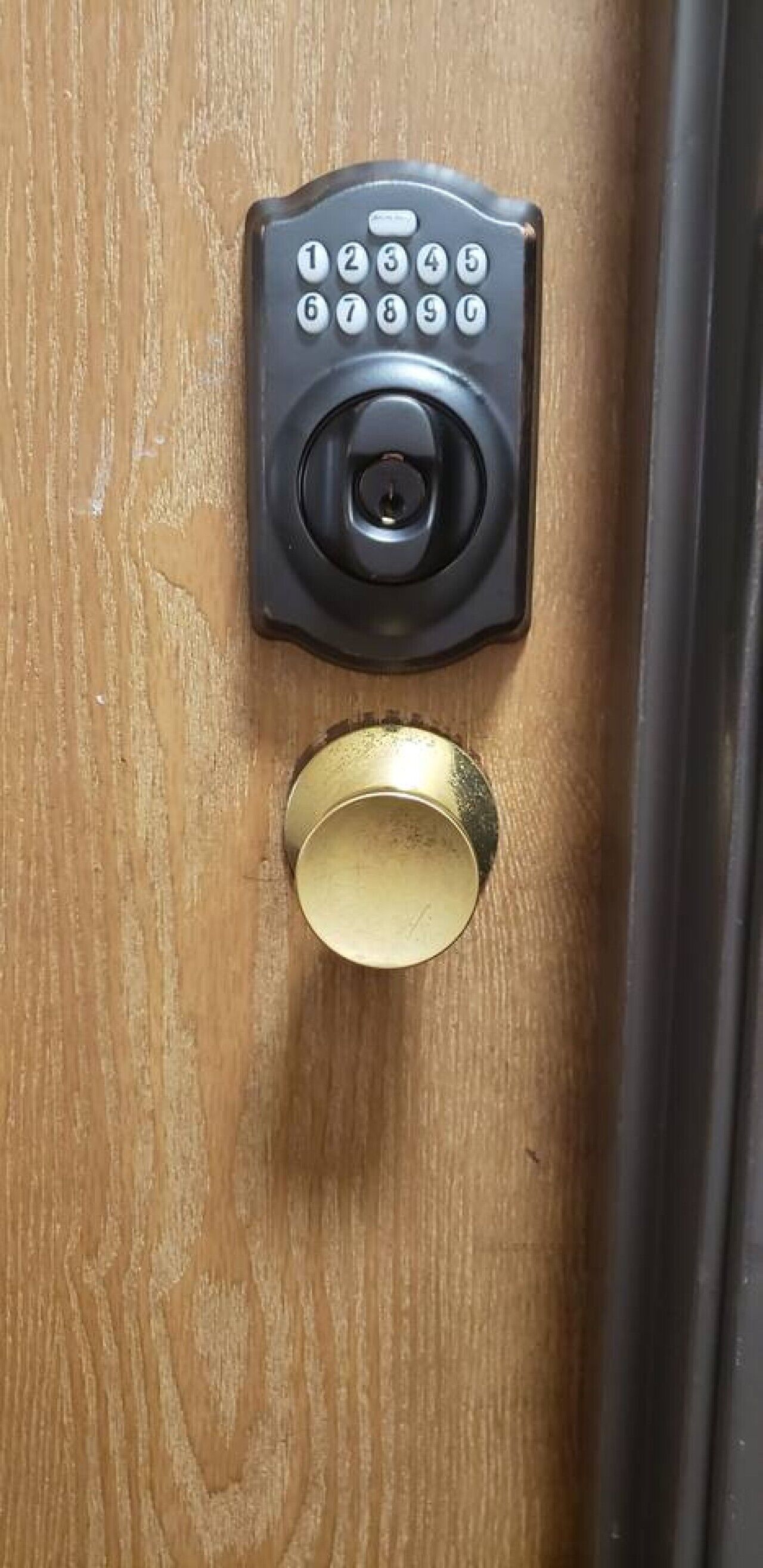 Une porte dotée d’un clavier pour ouvrir et d’une poignée de porte en laiton.