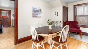 Un comedor con una mesa redonda, cuatro sillas, un jarrón con flores y una silla roja.