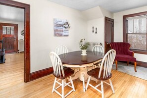 A dining area with a round table, four chairs, a vase with flowers, and a red chair. - KING bed home North of Downtown St. Cloud (St. Cloud)