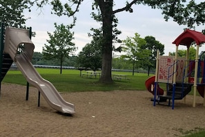 A playground with a slide and climbing structures, surrounded by trees and a picnic table. - KING bed home North of Downtown St. Cloud (St. Cloud)