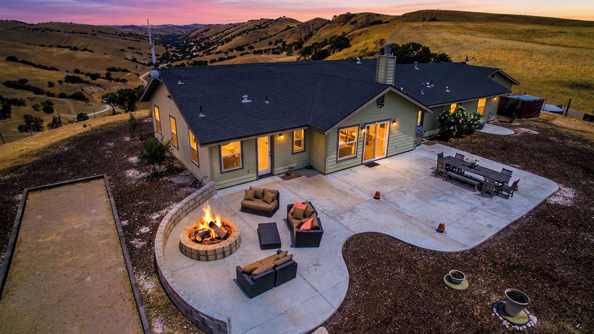 A house with a patio area featuring a fire pit, outdoor furniture, and a view of the surrounding landscape.