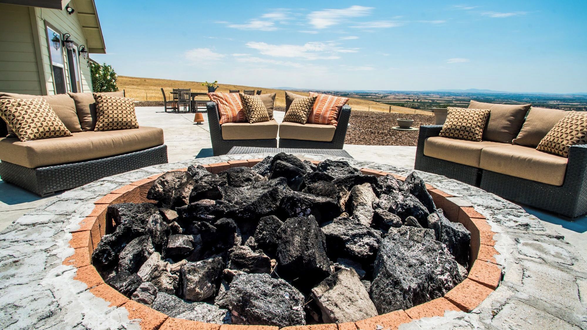 Un espacio al aire libre con fogata, sofás y vistas al paisaje.