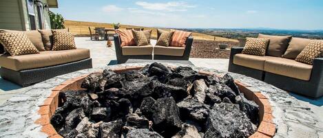 Un espacio al aire libre con fogata, sofás y vistas al paisaje.