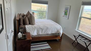 A bedroom with a bed, bedside table, lamp, and a view of the outdoors.
