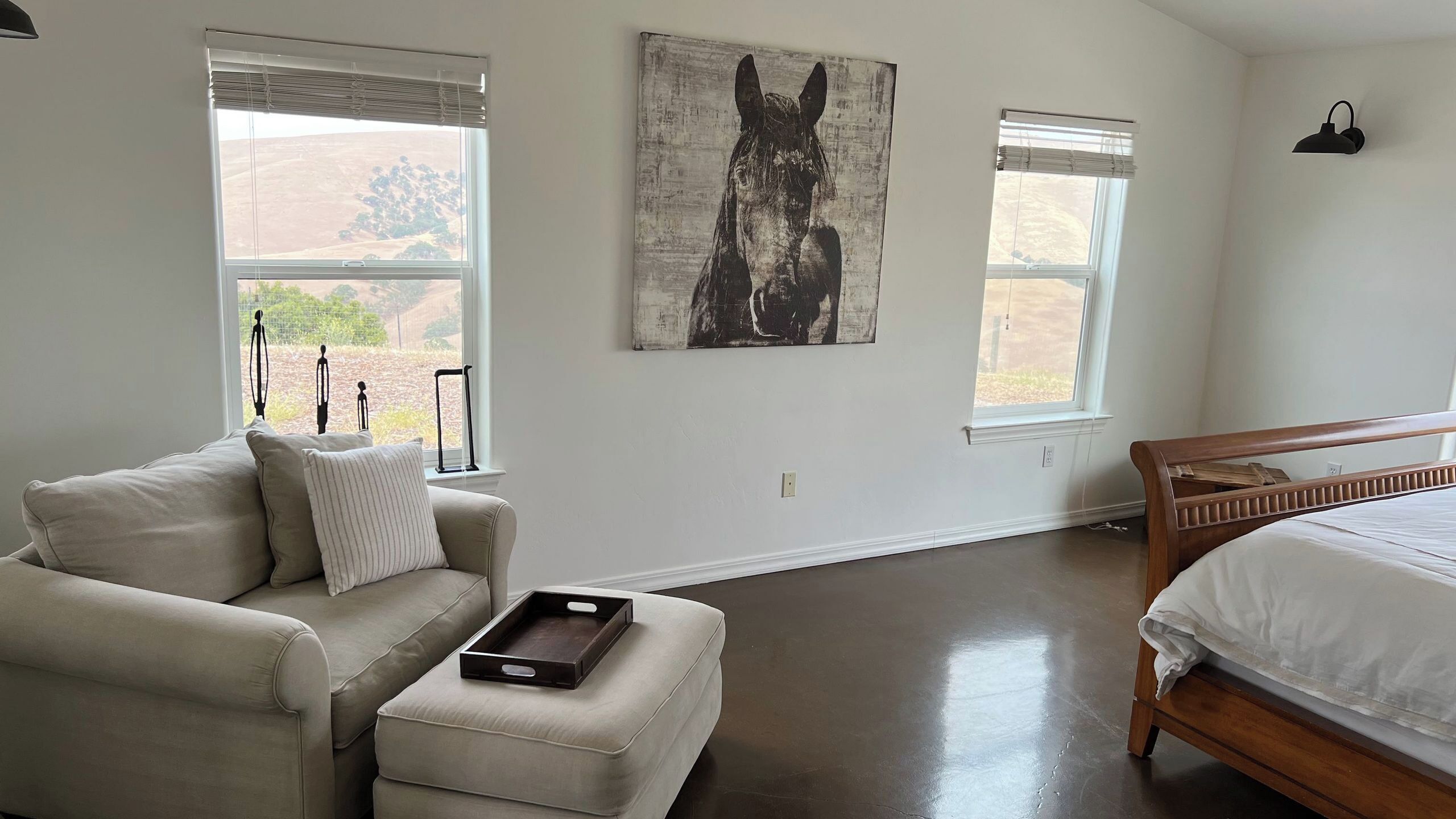 A bedroom with a bed, a sofa, a small table, and artwork on the wall.