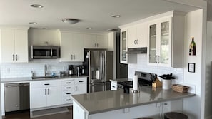 A modern kitchen with white cabinetry, stainless steel appliances, and a central island.