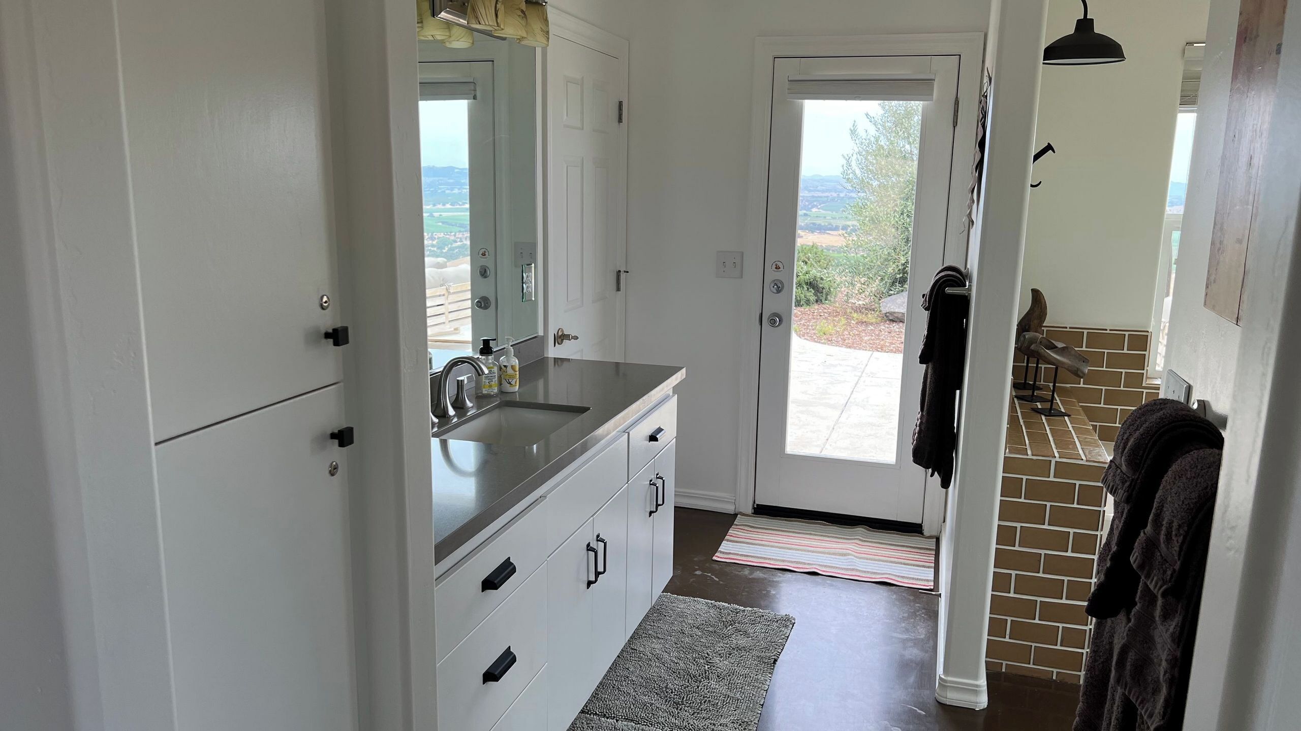 A modern kitchen with a large window, white cabinetry, and a built-in sink.