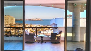 A balcony with a view of a coastal cityscape, furnished with wicker chairs and a small table. - Luxury Beachfront Villa in Sandy Beach - Ocean View - Sleeps 9 Max. Pet-Friendly (Puerto Peñasco)