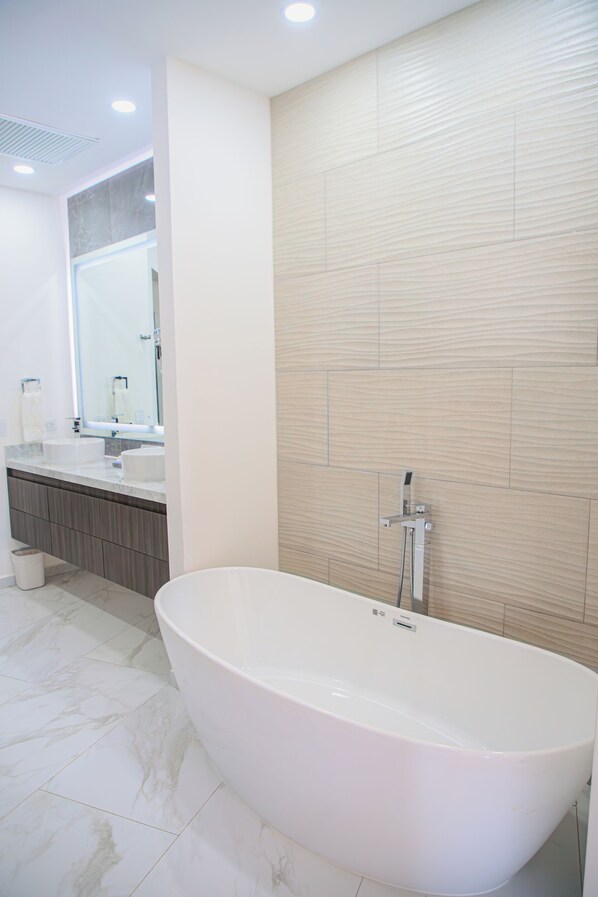 A modern bathroom with a freestanding bathtub, a vanity with a mirror, and a shower area.