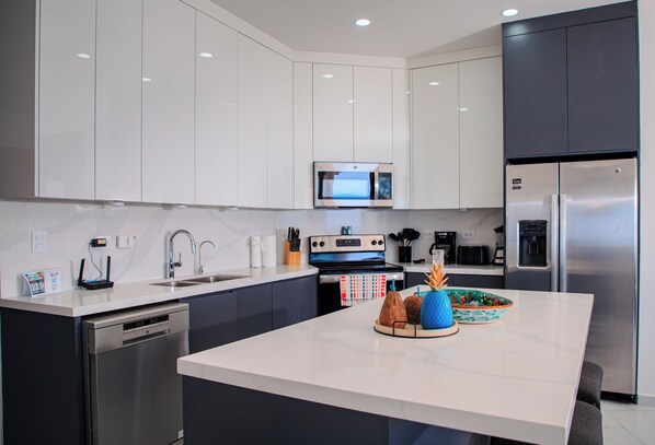 A modern kitchen with stainless steel appliances, a central island, and a microwave above the stove.