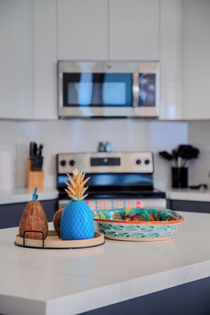 Una encimera de cocina con microondas, estufa y un cuenco decorativo.