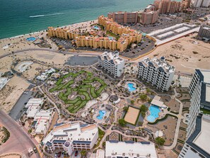 Een kustresort met meerdere hotelgebouwen, een strand en een golfbaan.
