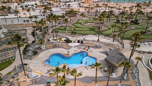An aerial view of a resort with a swimming pool, palm trees, and a golf course. - Luxury Beachfront Villa in Sandy Beach - Ocean View - Sleeps 9 Max. Pet-Friendly (Puerto Peñasco)