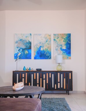 A modern living room with a round table, a blue rug, and a dark wooden cabinet with decorative panels.