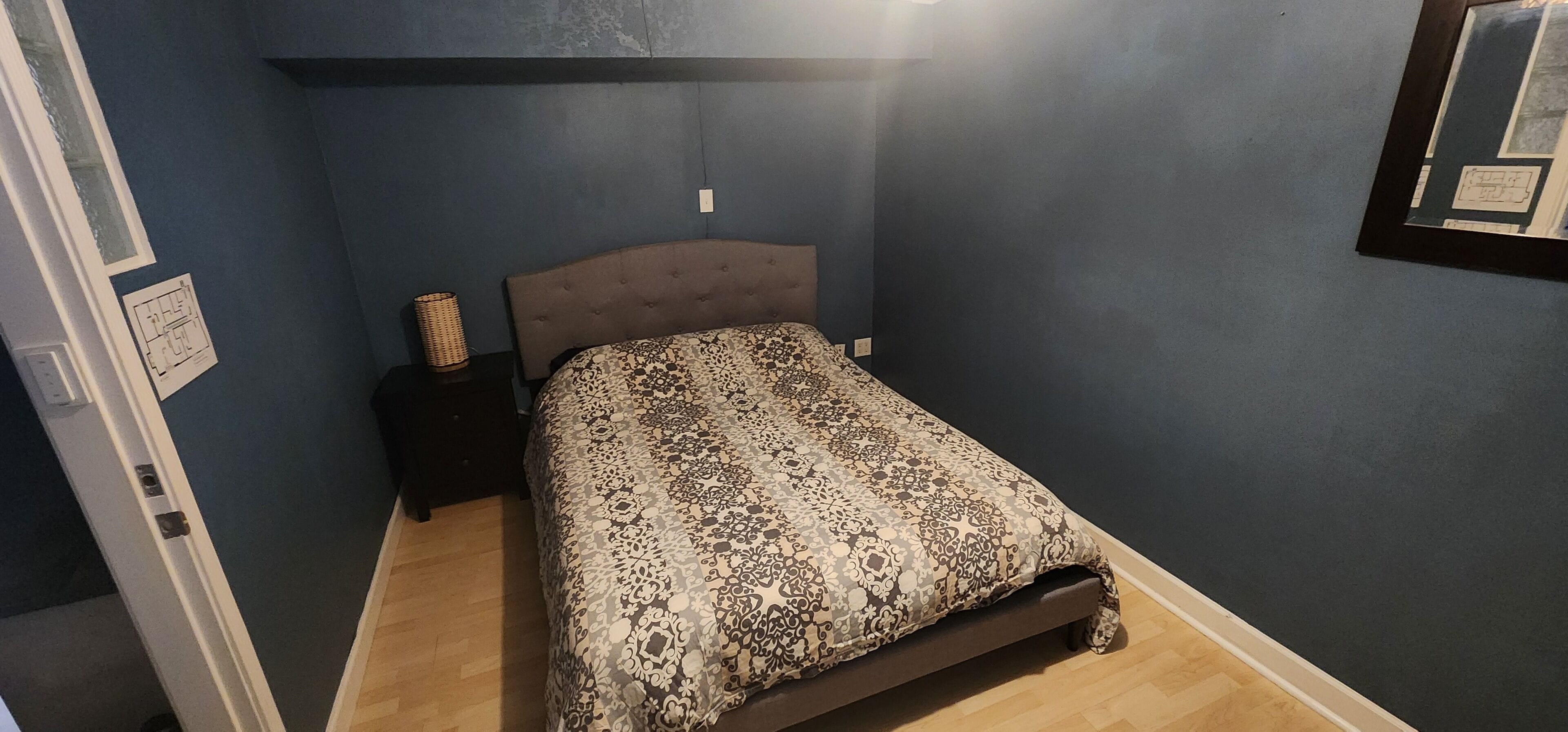 A bedroom with a bed, a nightstand, and a wall-mounted light fixture.