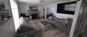 A living room with two sofas, a coffee table, a fireplace, a television, and a large window.