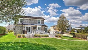A two-story house with a front porch, a well-maintained lawn, and a clear sky. - Bonnet Shores Beach Home- 3 Min Walk to Beach! (Narragansett)