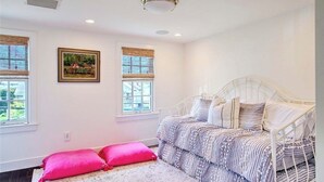 A bedroom with a white bed, two windows, and a ceiling light.