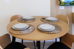 Una mesa de madera redonda con cuatro juegos de platos y cubiertos, acompañados por individuales tejidos.