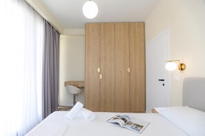 Una habitación de hotel con cama, armario de madera, escritorio y lámpara.