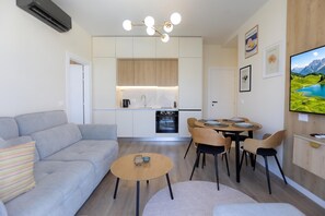 Una sala moderna con un sofá, una mesa de centro y un comedor con sillas y una mesa dispuesta para cuatro.