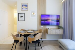 A modern living room with a dining area, a flat-screen TV mounted on the wall, and a minimalist design. - Seaside Serenity Palm Apartment, Vlore, Albania (Vlore)