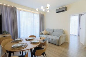 A dining area with a round table set for four, a sofa, and a TV on a stand.