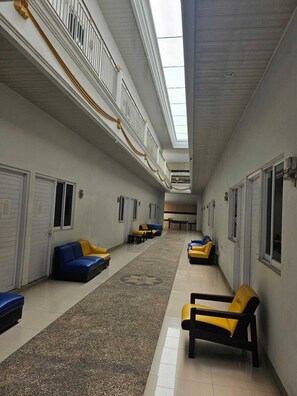 A corridor with seating areas, doors, and a skylight.