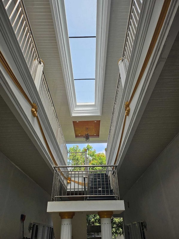 Un intérieur spacieux avec un balcon central, des colonnes blanches et une verrière.
