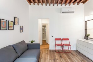 A modern living space with a grey sofa, red chairs, a white wall with framed artwork, and a wooden ceiling. - Old Town Living in historic center & A/C, Genova, Italy (Genova)