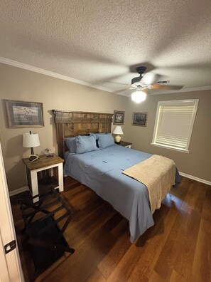 A bedroom with a bed, bedside tables, a ceiling fan, and a window with blinds.