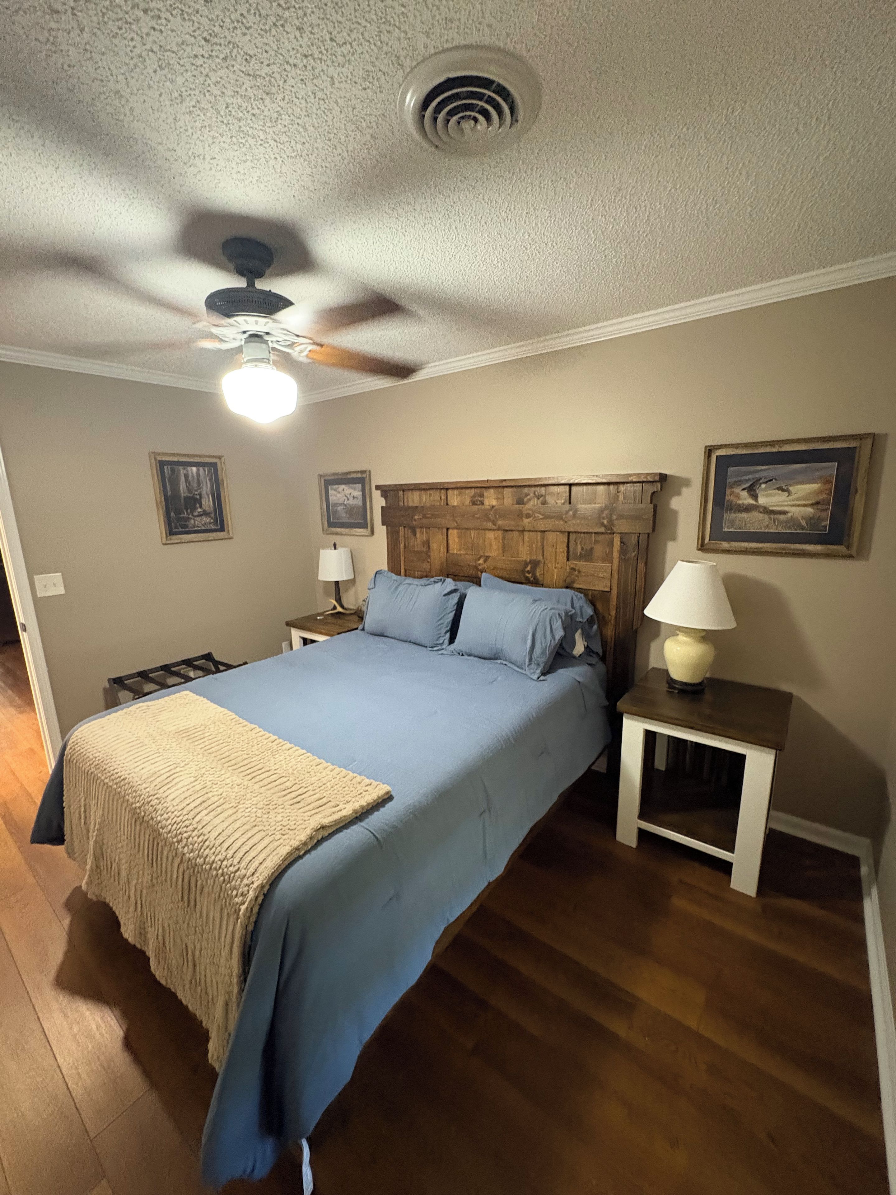 Una camera da letto con un letto, un comodino, una lampada e una ventola a soffitto.