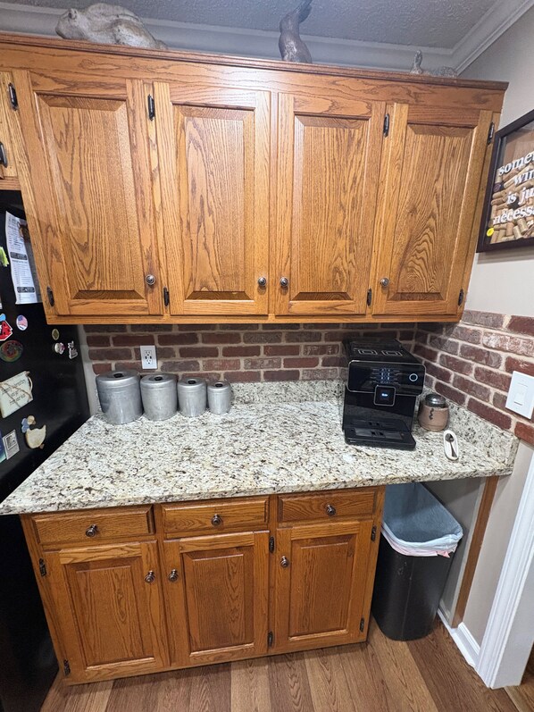A kitchen with wooden cabinets, a granite countertop, and a coffee maker.